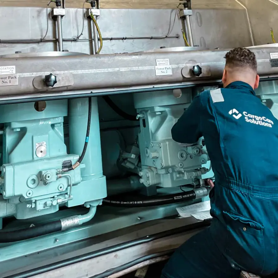 A man in a blue jumpsuit working on a machine.