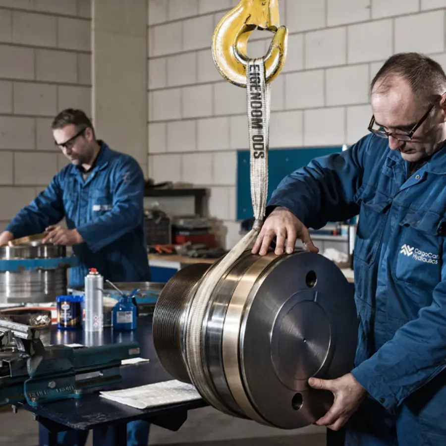 Two men working on a large metal cylinder.