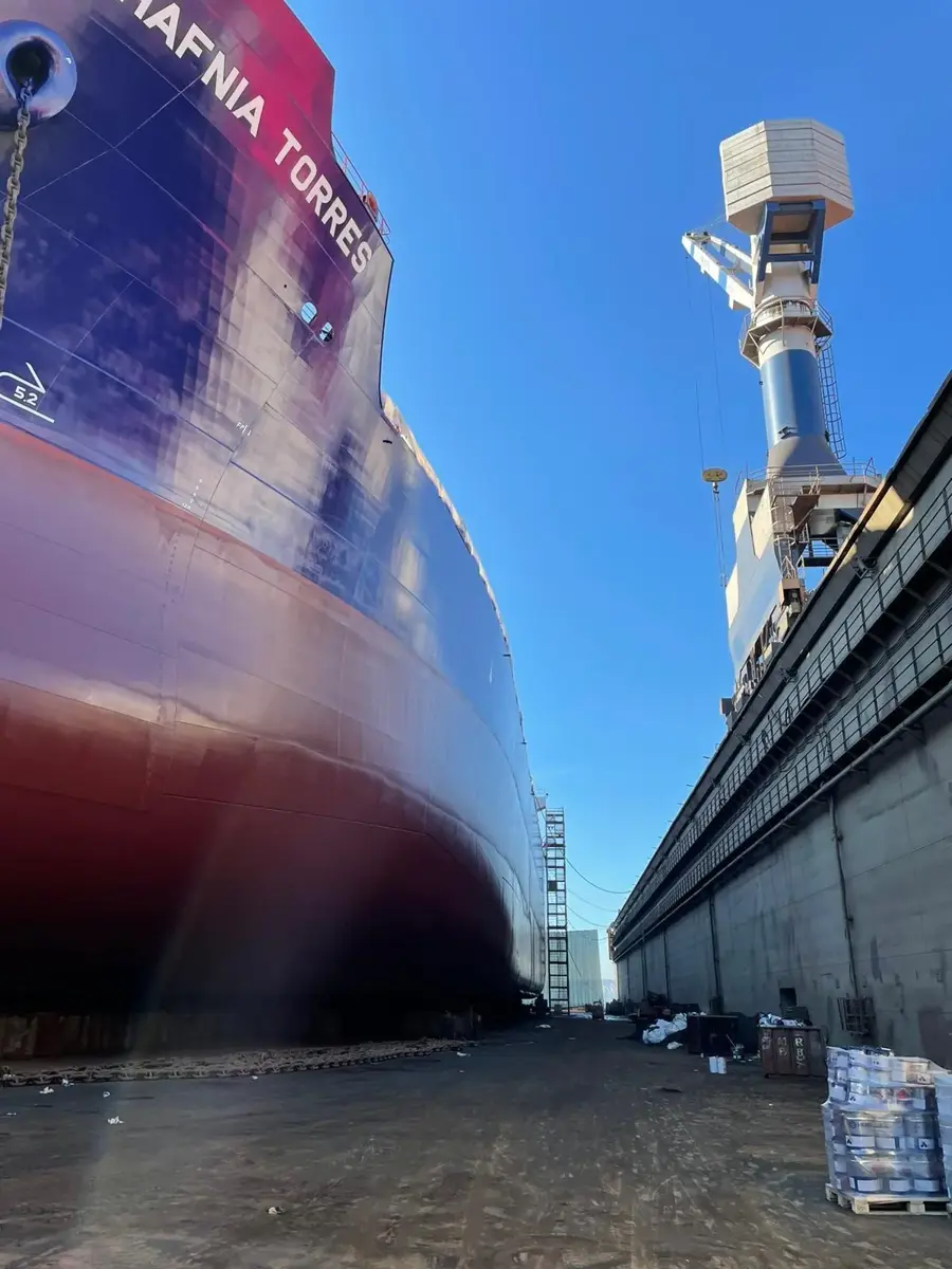 A large ship is docked at a pier.