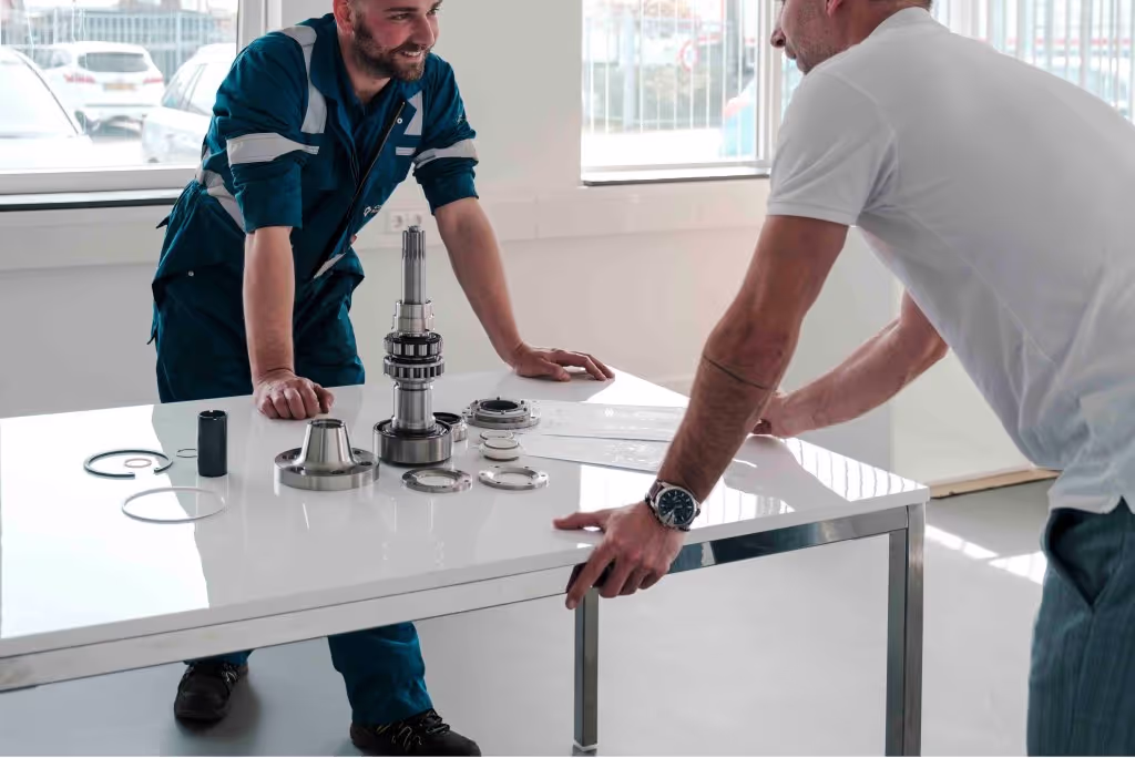 Two men around a table and a cargo pump talking.