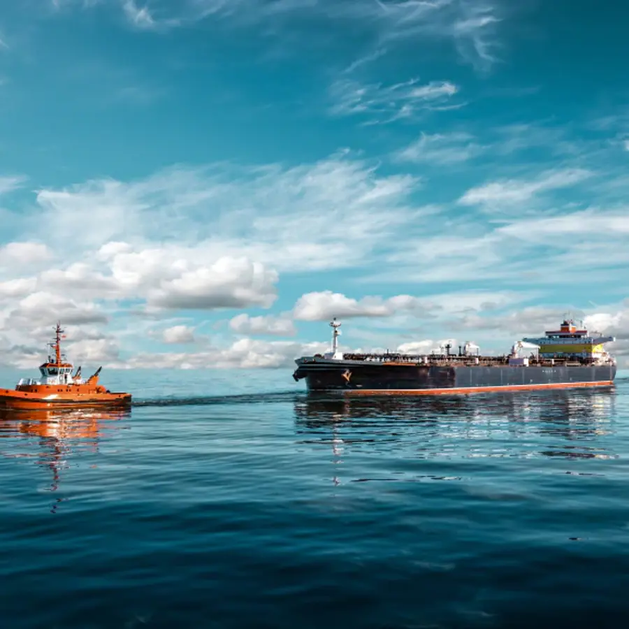 A large ship is sailing in the ocean with a small boat in the water.